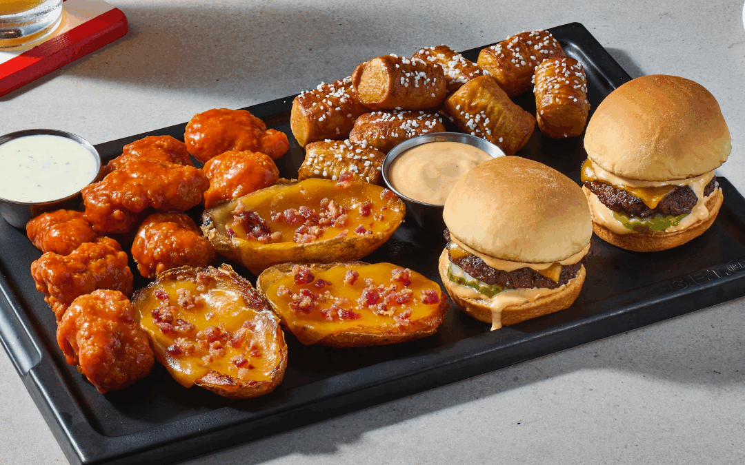 TGI Fridays appetizer sampler with wings, potato skins, pretzels, and sliders on a serving tray