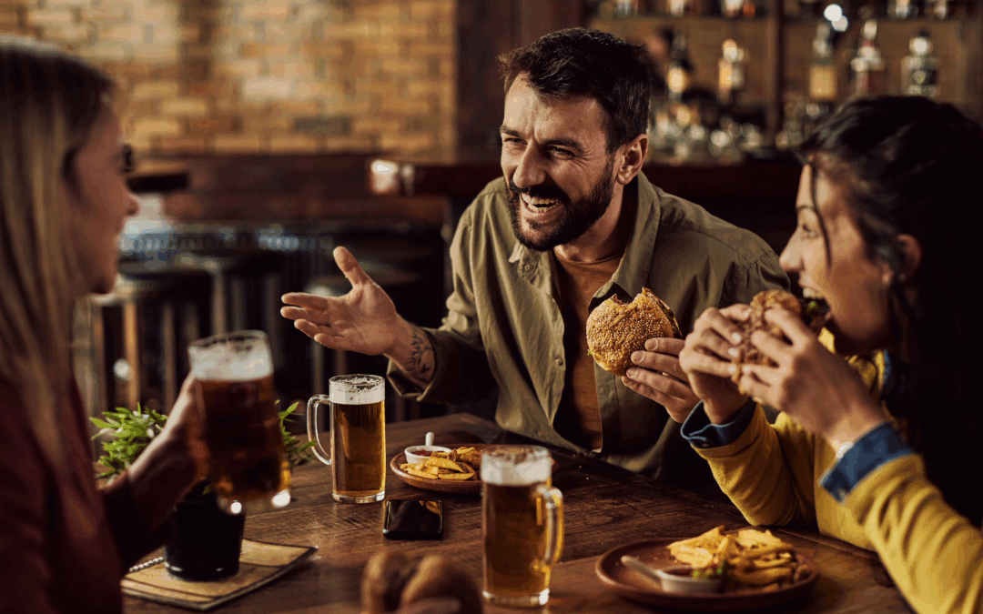 Friends enjoying burgers and beers at a restaurant, sharing laughs during a Friday night out at TGI Fridays.
